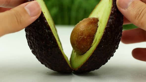 4K Video close-up Women s hands hold two cut halves of fresh Green Avocado Front view.