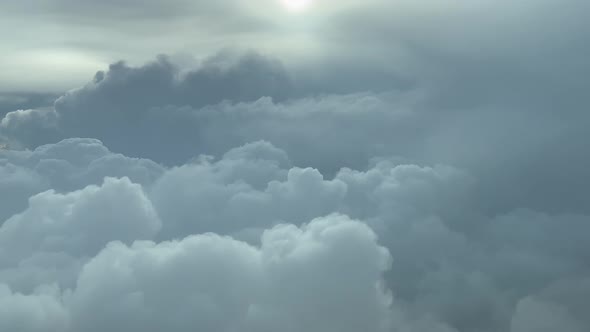 PILOT VIEW, BACKLIT - Descending towards stormy cumulonimbus clouds, commercial flight