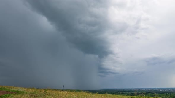 Timelapse Storm clouds move across the sky over the hills, rain in the distance. Uhd