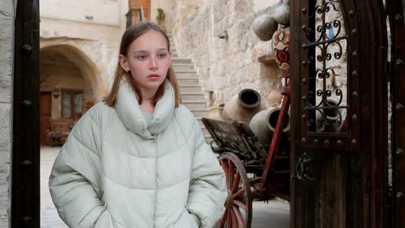 Thoughtful Young Girl Standing in Doorway in Old Town