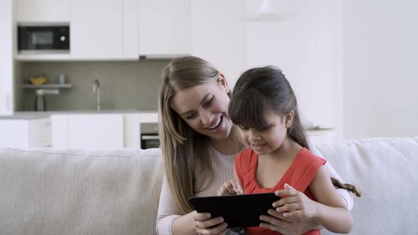 Mom and Cute Little Daughter Using Online App on Tablet