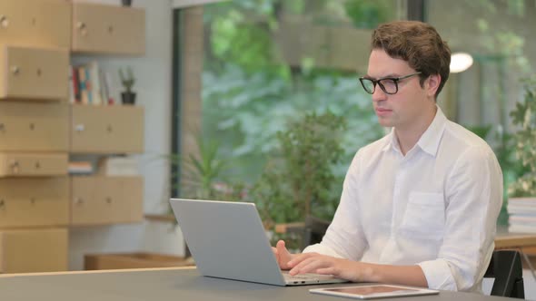 Young Man Working on Laptop in Modern Office