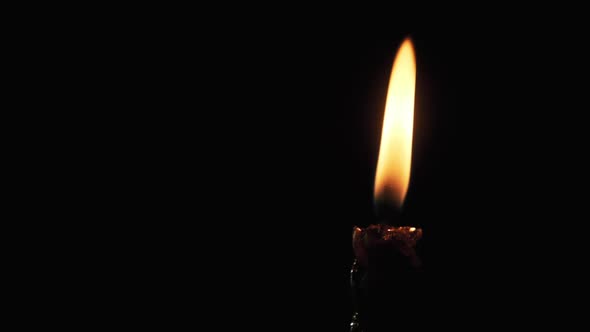 A Single Candle Is Lit on a Black Background. Candle Flame in the Dark.