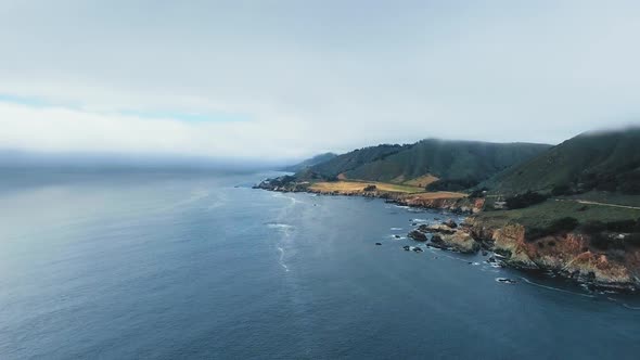 Aerial drone shoots a mountainous ocean coast with a road (California, USA)