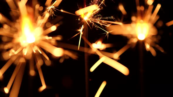 Burning sparklers on black background. Burning New Year sparklers. 4K UHD video