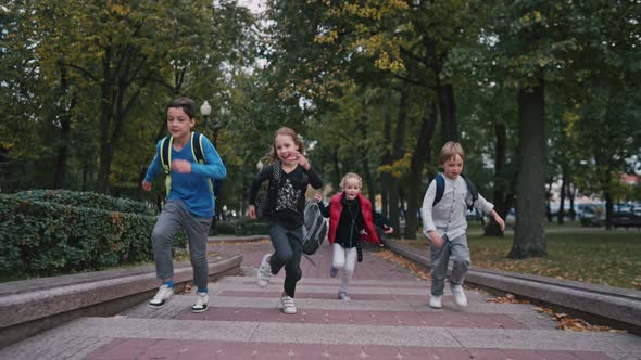 Schoolchildren with Backpacks Running Up Stairs Near School