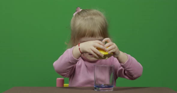 Beautiful Young Girl Squeezes Lemon Juice with a Grimace on Her Face