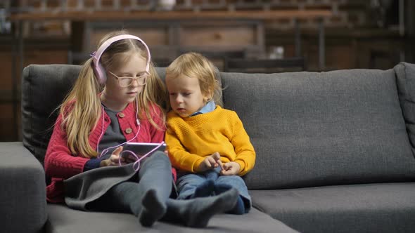 Sweet Little Siblings Using Tablet Pc on Sofa