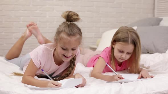 Kids Drawing Pictures While Lying on Bed