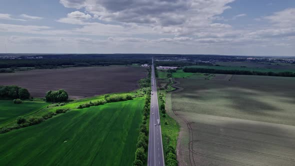 Cars Driving Along the Rustic Asphalt Road Between Fields