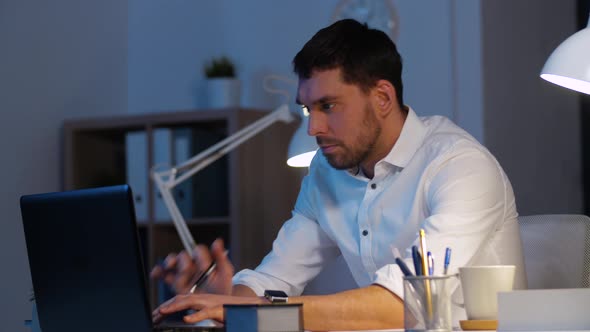 Businessman with Laptop and Coffee at Night Office 31