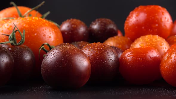 Cherry tomatoes on a black background in water drops.