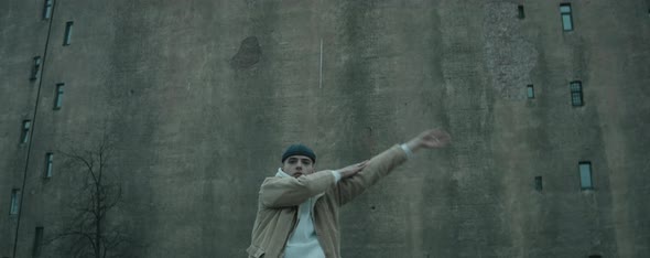 Stylish Man Dancing Vogue to Camera against Old Concrete Building