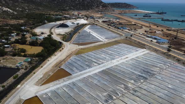 Birds eye view of vast salt flats harvesting sodium chloride, spread along mountains in Phan Rang, V