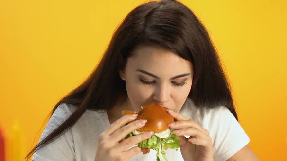Brunette Girl Eating Burger at Cafe, Displeased With Disgusting Sandwich Taste