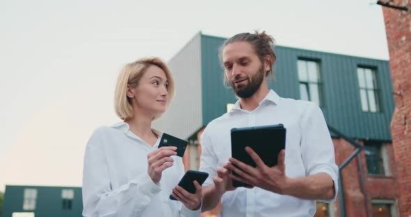 Business People Shopping Online Using Digital Tablet and Credit Card Outdoors Near Office Buildings