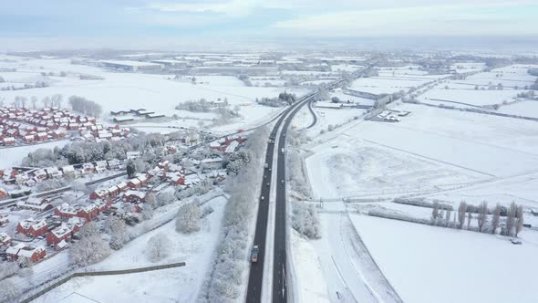 Aerial view of snow covered countryside and highway road