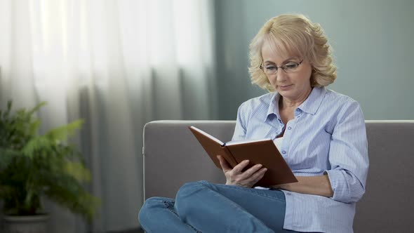 Middle-Aged Housewife Sitting on Sofa and Reading Interesting Book, Hobby