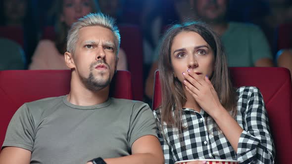 Closeup Couple Shocked Watching Horror Scene Film with Hand Near Mouth Negative Emotion at Cinema