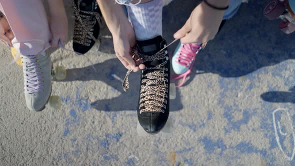 Overhead View of Young Women Hands Tying Laces on Retro Rollerskates