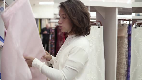 A Beautiful Brunette Chooses a Fabric in a Tissue Store