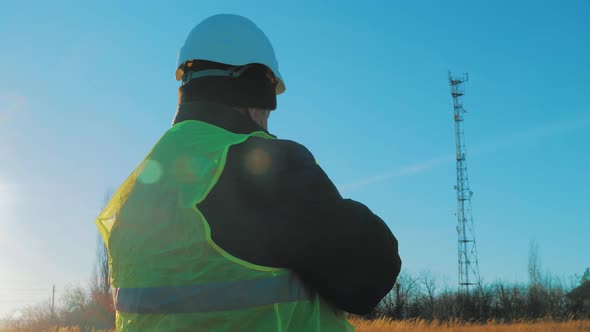 Silhouette Engineer Working on Digital Tablet, with Satellite Dish Telecom Network on