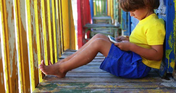 Boy using digital tablet near colorful beach hut