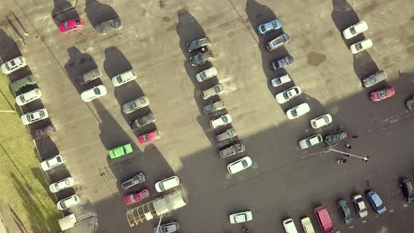 Top aerial view of many cars on a parking lot of supermarket or on sale car dealer market.