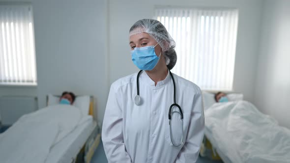 Tired Nurse in Coronavirus Face Mask Looking Back at Ill Patients Shaking Head Looking at Camera