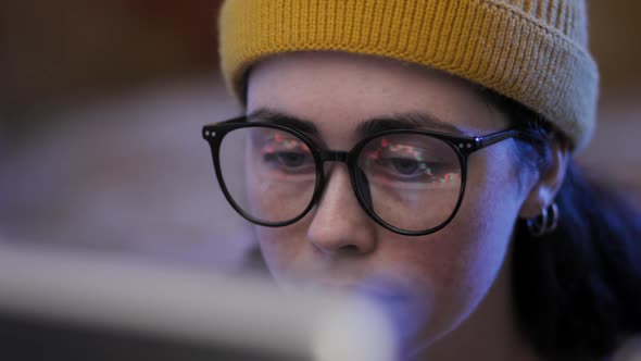 Portrait of a Young Caucasian Woman Trader in Hat Wearing Eyeglasses Looking at a Computer Screen