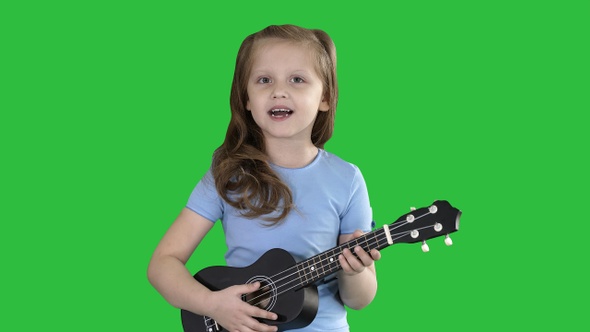 Little girl singing and playing small guitar while walking