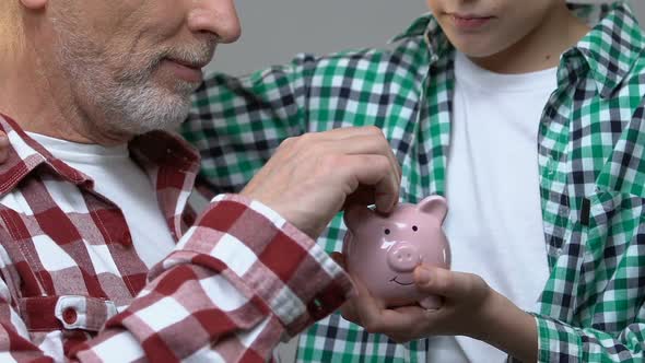 Boy Hugging Grandfather, Old Man Putting Coins in Piggy Bank, Savings Concept