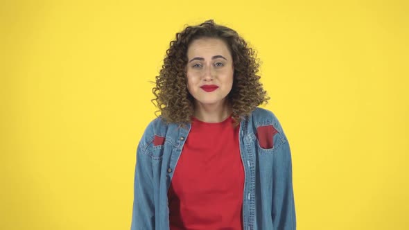 Surprised Girl with Curly Hair Rejoices at What He Heard on Yellow Background at Studio, Slow Motion