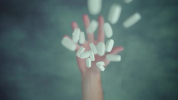 Hand Throwing Up Handful of Medicines Above Green Table