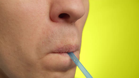 Close-up of a man's face with a plastic straw, yellow background