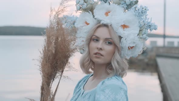 Woman in Ukrainian national costume with a wreath on her head. Embroidery. View of the river. Woman