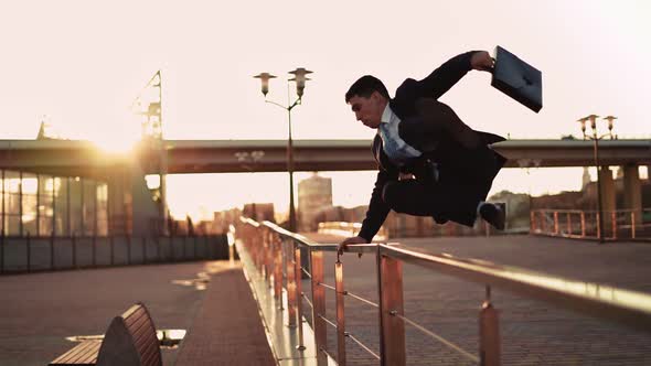 Businessman in Jacket and Tie Jumps Over an Obstacle on Background Sunset Light