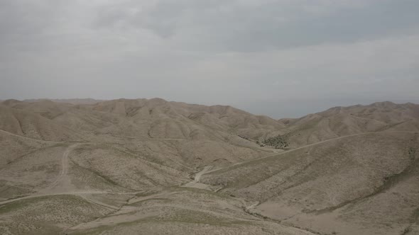 man laying on a hill in the clam desert, aerial fly over shot, Israel