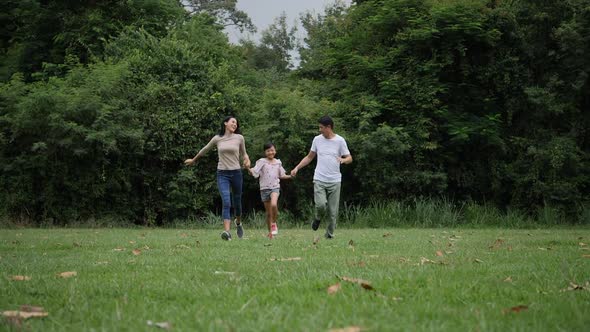 Slow motion of parents with daughter running enjoy in the park