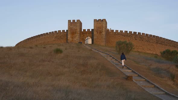 Woman going up on the stairs to Arraiolos castle at sunset in Alentejo, Portugal