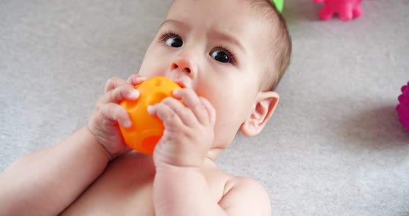 Infant Childhood Concept  Closeup of Smiling Happy Baby Plays with a Teether