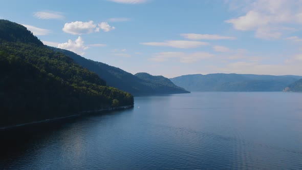 Boats on lake Teletskoye between mountains with blue clear sky in Altai