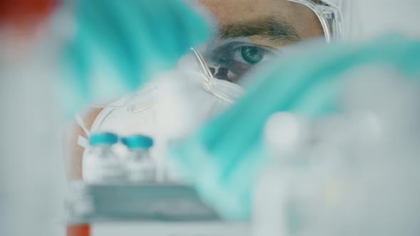 Scientist Examines a Small Vial with COVID19 Vaccine