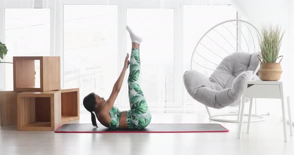 Sporty black woman is doing abs exercises on floor.