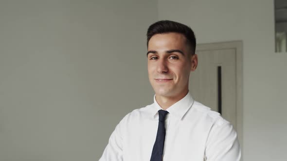 Portrait of Confident Man in Suit Turns at Camera with Smile and Crosses Hands