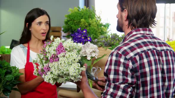 Female staff assisting man in selecting flower bouquet