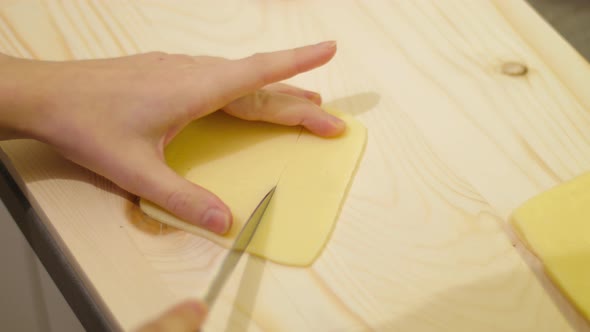 Close up of hands slicing Cheddar strips