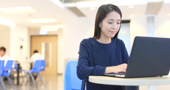 Woman doing homework on laptop computer inside university campus