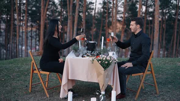 Elegant Couple Serving Dinner Outdoors Sipping Glasses of Champagne