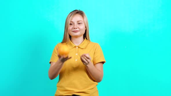 The Young Woman Holds an Orange in Her Hands and Promotes a Healthy Lifestyle